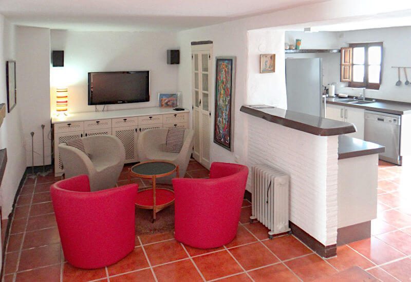 Wohnzimmer mit Stühlen und kleinem Tisch offen zur Küche im weißen Dorf