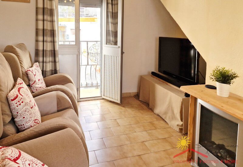 zitkamer met bank en tv, een glazen deur naar het balkon en een houtkachel