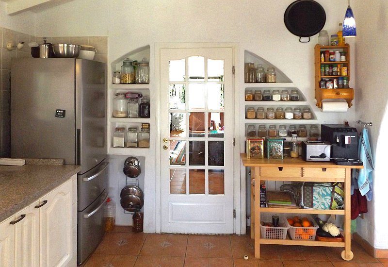 De keuken heeft veel opbergruimte en een deur naar de woonkamer.