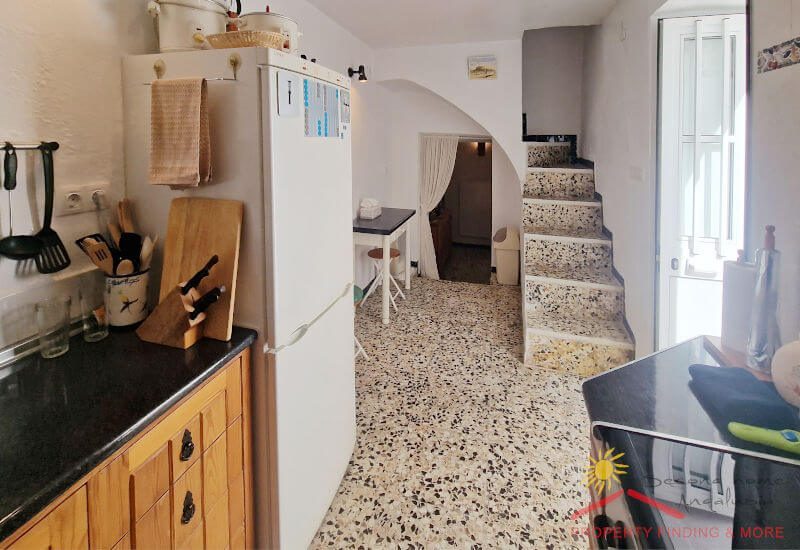 Van de keuken naar de hal met deur naar de patio en de trap naar boven