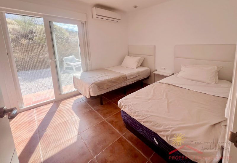 Das Zweibettzimmer mit 2 Betten und einer doppelten Glastür zur Terrasse