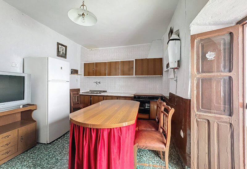 Eine große Küche mit einem Holztisch und einer einfachen Küchenzeile