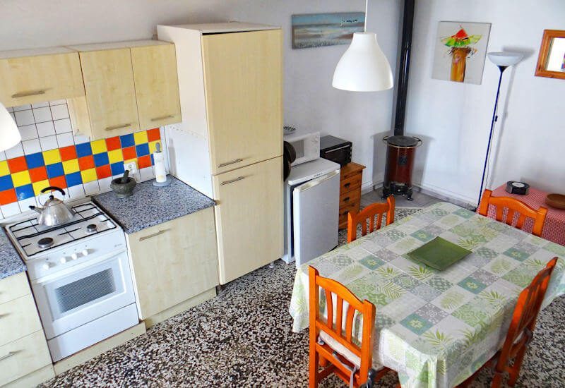Küche mit Holzofen in der Ecke mit Esstisch und Fenster im typischen andalusischen Dorf