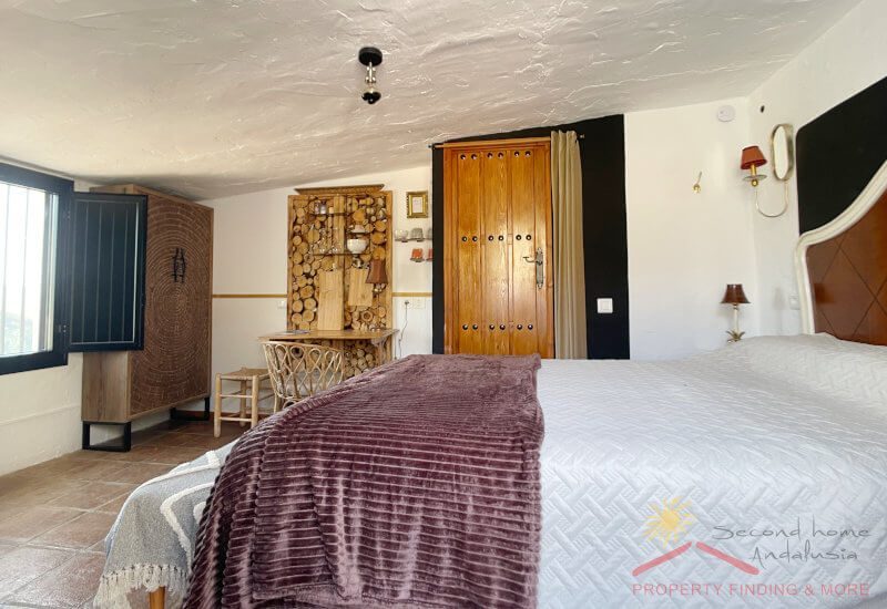 Een grote slaapkamer met tweepersoonsbed en rustieke inrichting