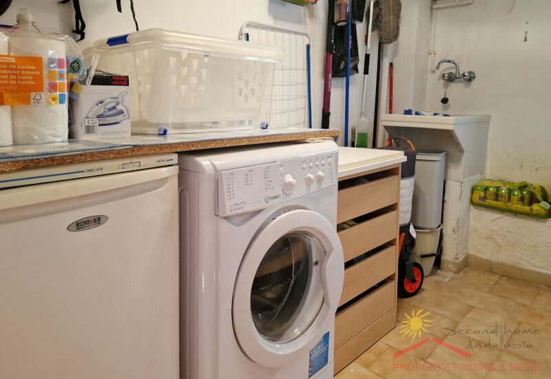Er is een bijkeuken met wasmachine in de kelder