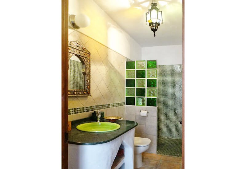 The green bathroom si tiled in green and has a shower