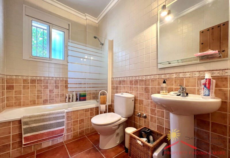 A family bathroom with tube and shower and a window for natural light