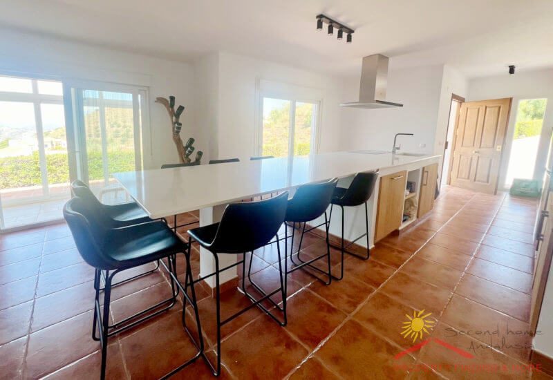 Open-plan kitchen with many windows and long dining table
