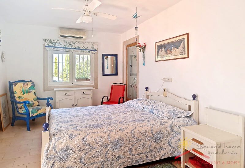 Large 2nd bedroom with wide bed and chair, window and ceiling fan