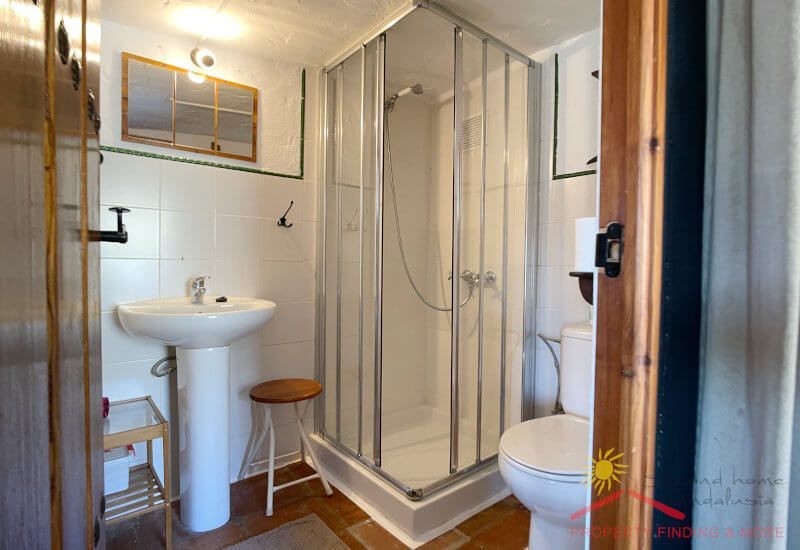 Een badkamer met douche en toilet bevindt zich op de bovenverdieping
