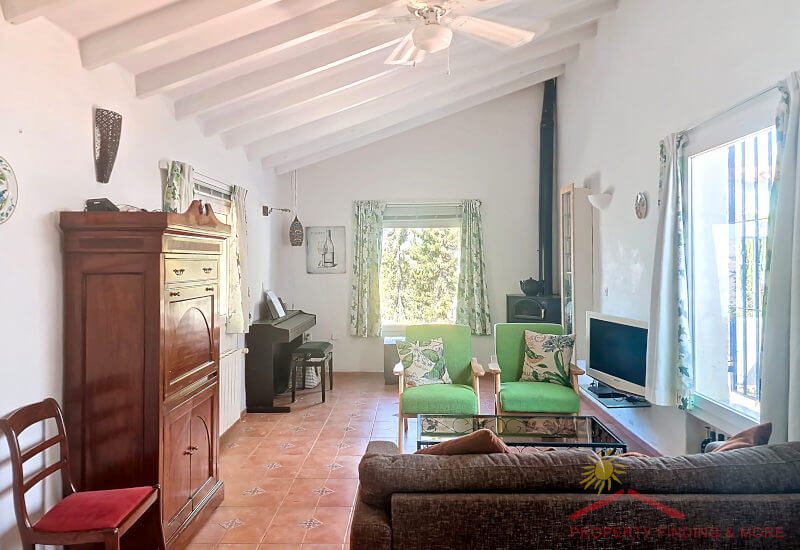 Living room with sitting area and fireplace, as well as windows and a sloping roof with beams