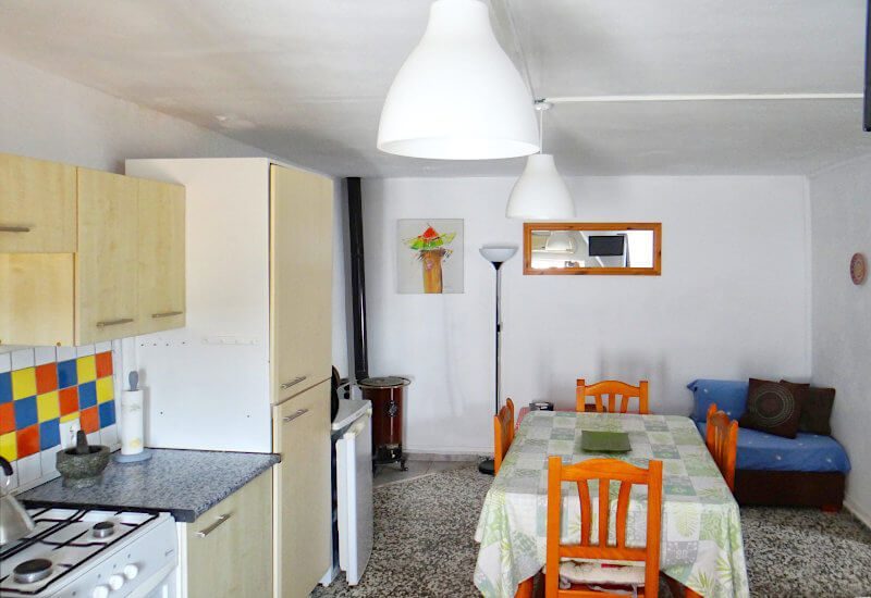 Keuken met houtkachel met eettafel en fauteuil in Spaans dorp