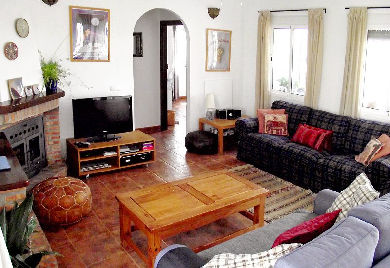 The lounge has a fireplace and is light up by many windows.