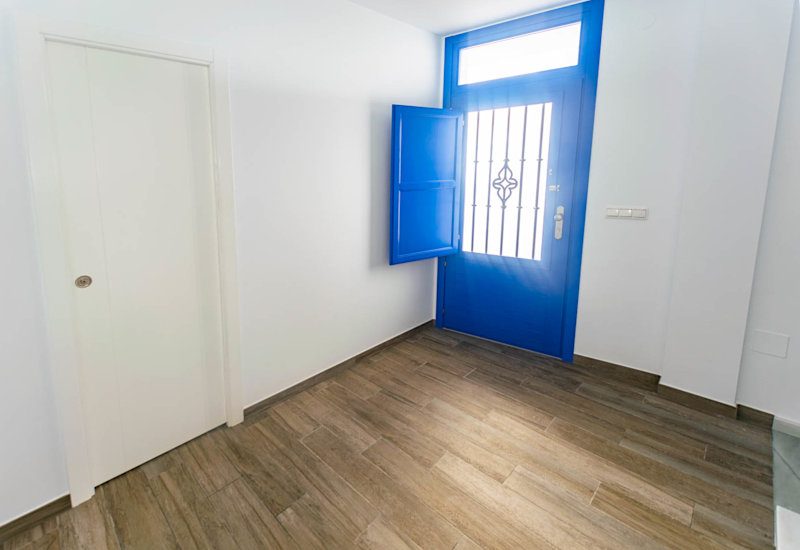 Die Haustür ist blau und hat ein Fenster im typisch spanischen Stil. Sie führt zu einer kleinen Eingangshalle.