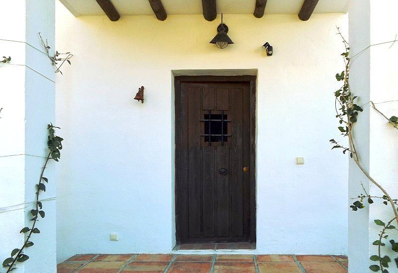 Photo of covered front entrance with wooden door.