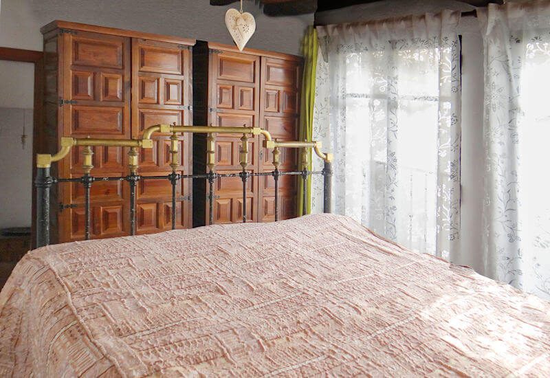 grote slaapkamer met twee openslaande deuren en een grote houten kledingkast