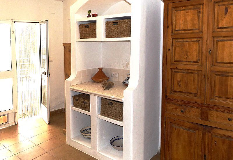 The kitchen is spacious and has a constructed shelf as well as a cupboard.