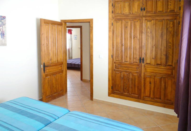 De gastenkamer heeft een twee bedden en een ingebouwde kast met houten deur