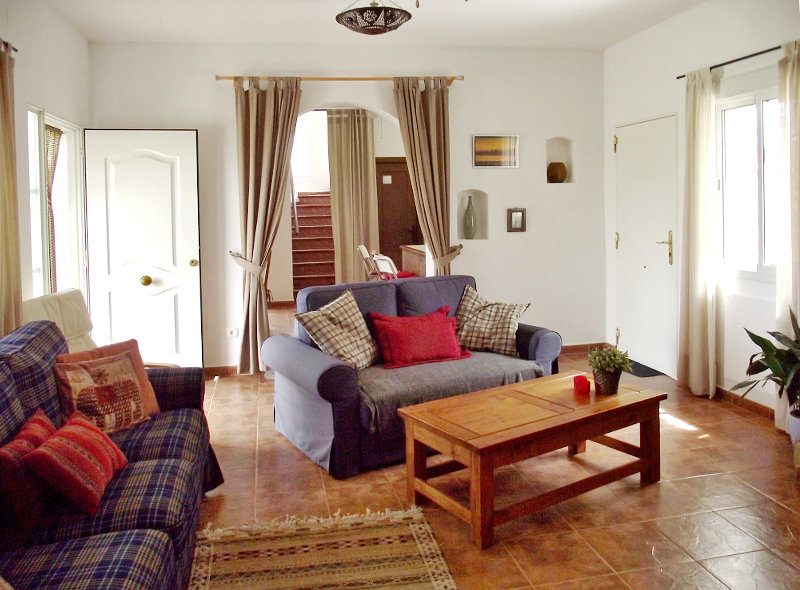 Lounge with sofas an entrance from the terrace and staircase to the second floor