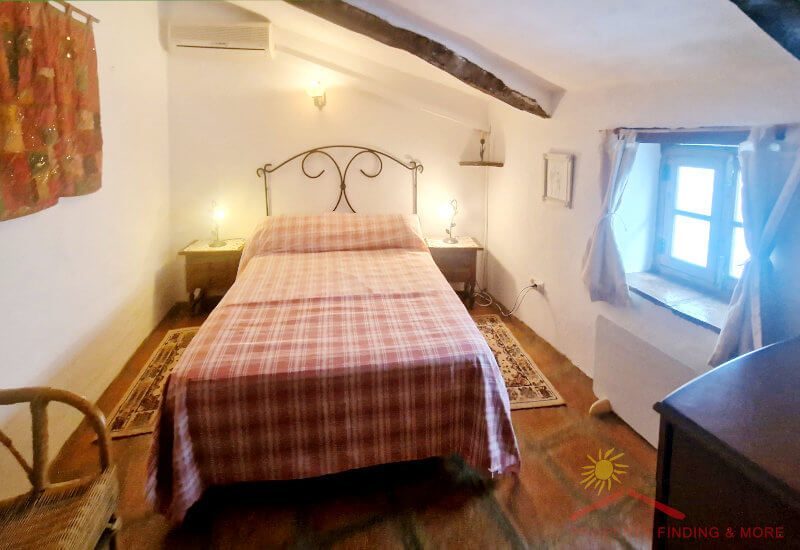 The master bedroom has a king-size bed and a small window overlooking the street