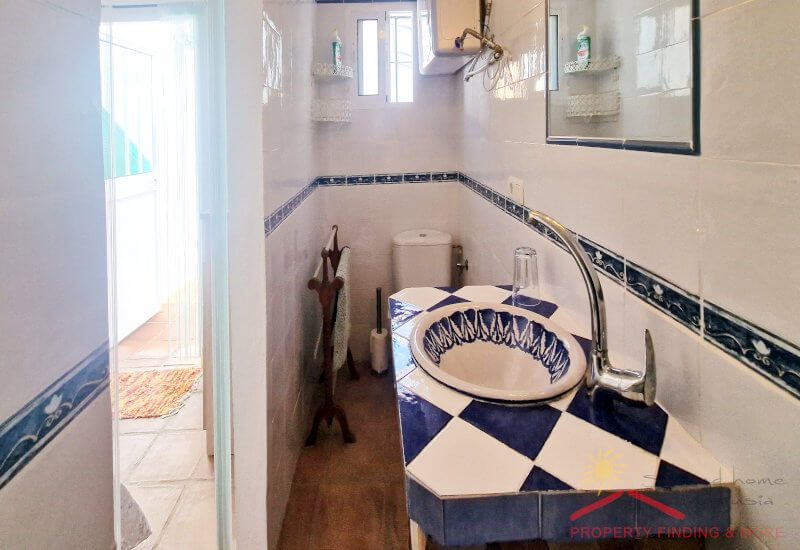 The small en-suite guest bathroom has a coulorful tiled basin 