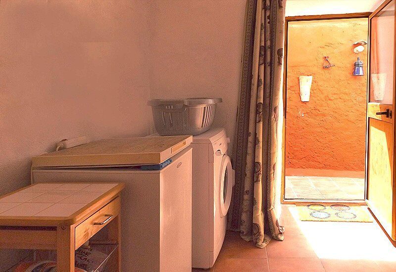 Hauswirtschaftsraum mit Tiefkühltruhe und Waschmaschine mit einer Tür zum kleinen Innenhof