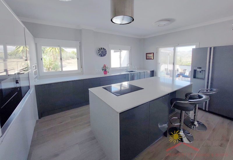 a big modern fully equipped kitchen with windows and glass door to the terrace.