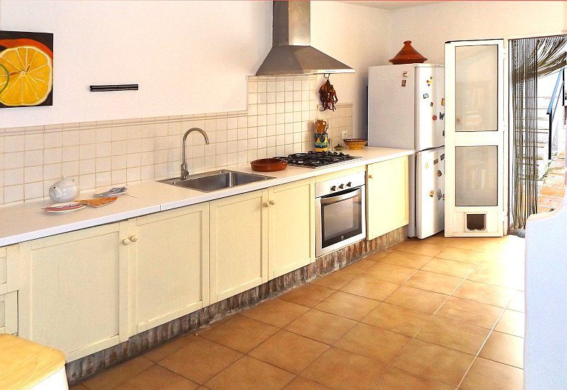 Foto van de modern ingerichte keuken met een glazen deur naar het binnenterras.