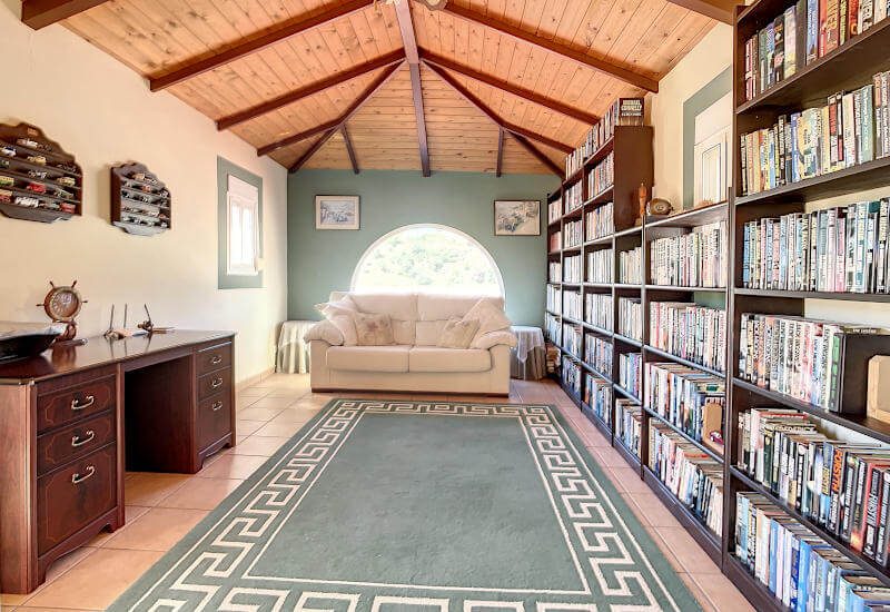 Die Bibliothek befindet sich auf der ersten Ebene mit einem langen Bücherregal, einem Sofa und einem Schreibtisch