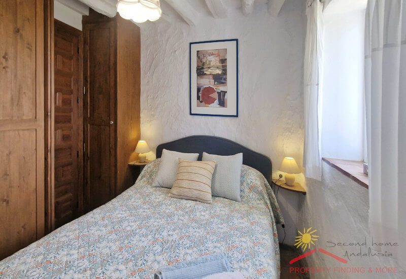 Foto van de logeerkamer met tweepersoonsbed en nachtkastje.