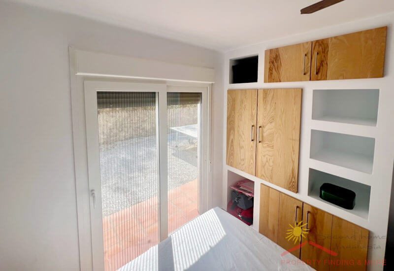 Hoofdslaapkamer met ingebouwde wand en grote glazen deuren naar het terras