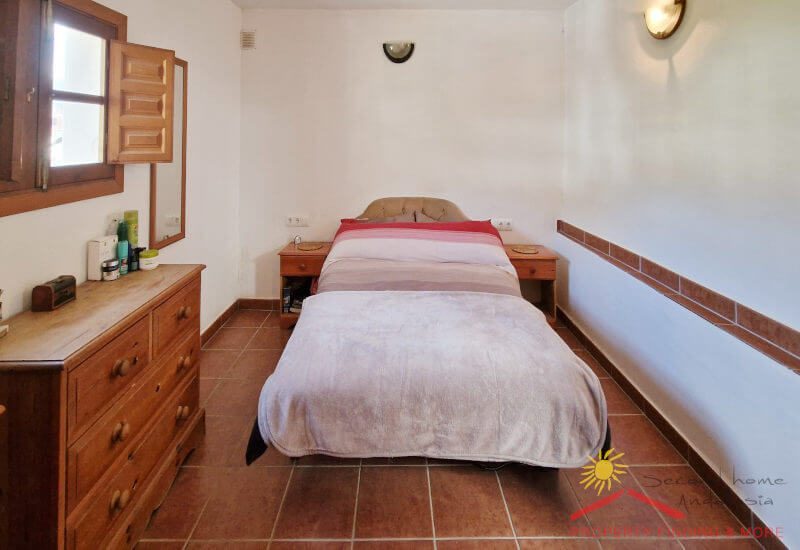 Hoofdslaapkamer met kingsize bed en klein houten raam