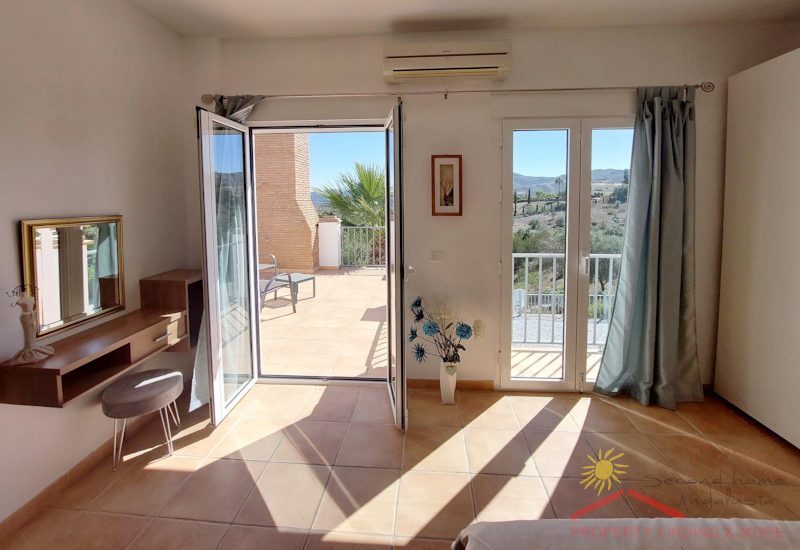 ein Schlafzimmer mit zwei Flügeltüren zur oberen Terrasse