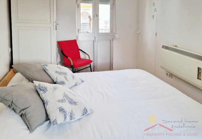 Slaapkamer 3 met tweepersoonsbed en metalen deur naar het balkon, een kleine kledingkast, stoel en verwarming