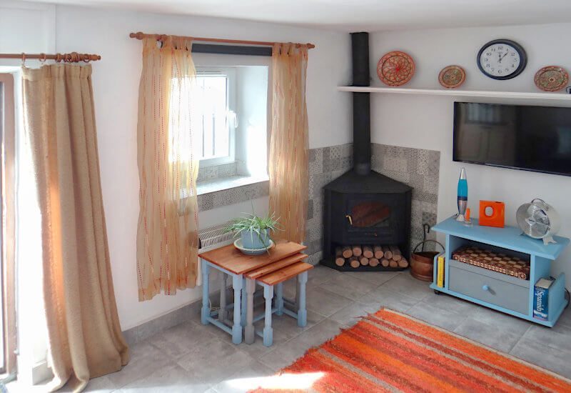 Rustieke woonkamer met raam en houtkachel in Sedella