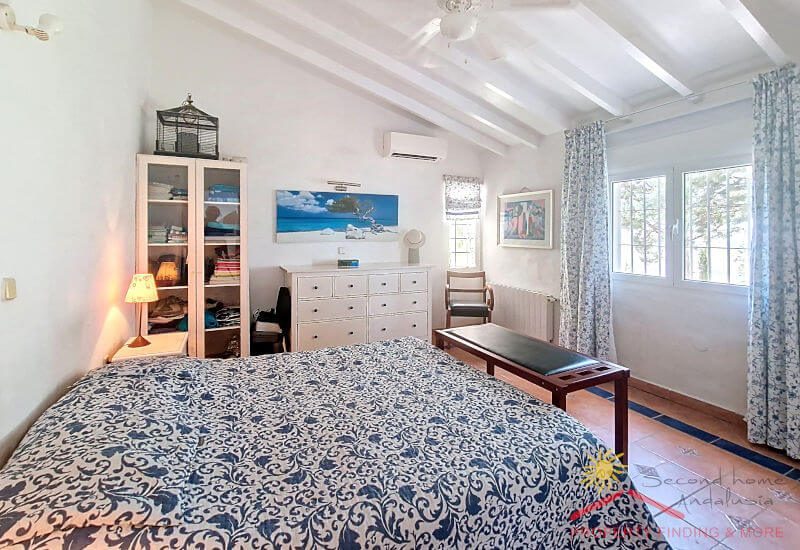Master bedroom with double bed, window, and sloping roof with beams
