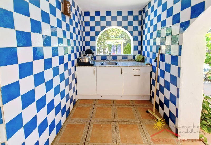 Sommerküche mit blau-weißen Kacheln und Bogenfenster