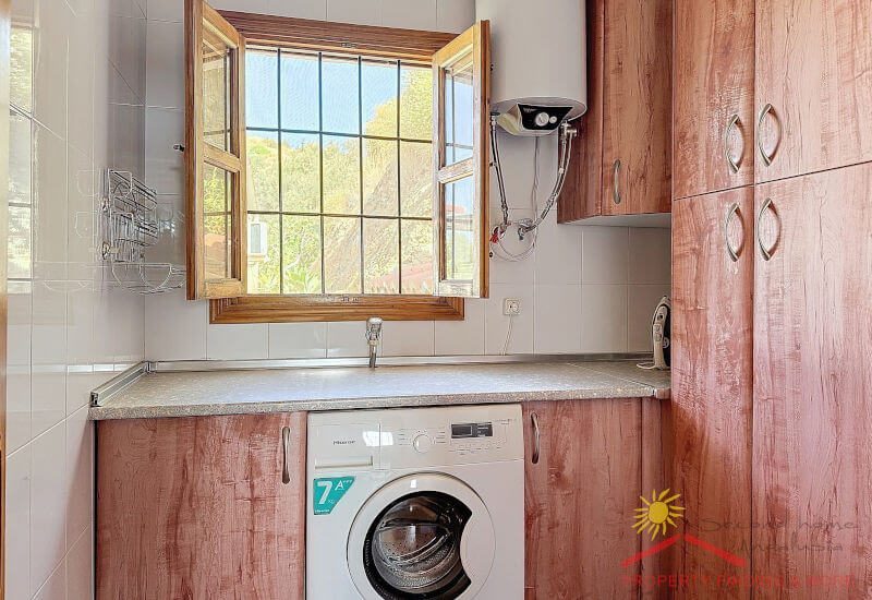 Lichte bijkeuken met wasmachine en kasten