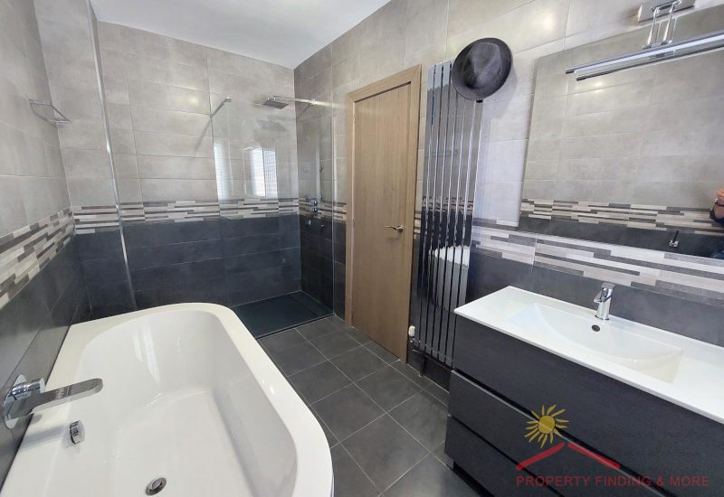 een grote familiebadkamer met badkuip, een ruime douche en verwarming met moderne tegels