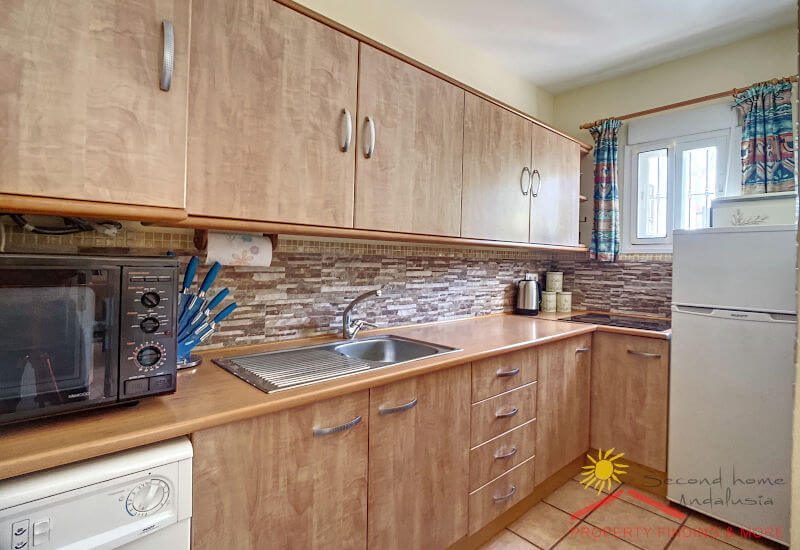 fully equipped flat kitchen with a small window