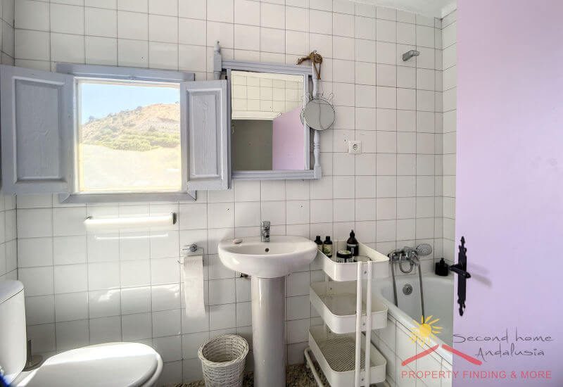 Badezimmer mit Badewanne, Toilette und Waschbecken und einem kleinen Fenster