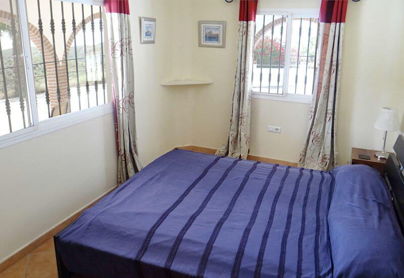 Hoofdslaapkamer met king-size bed en raam naar het terras