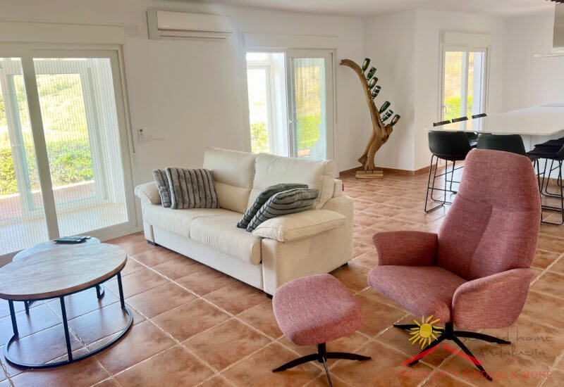 Woonkamer met bank en TV-fauteuil en openslaande deuren