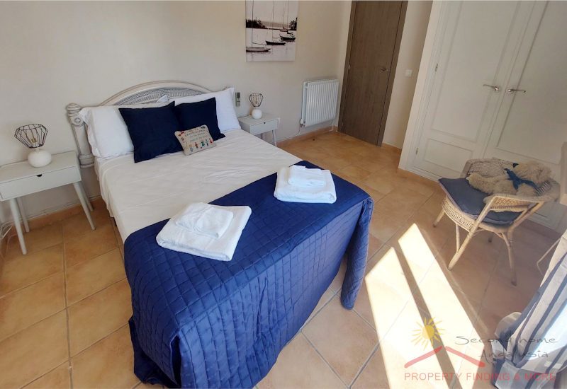 grote slaapkamer met kingsize bed en witte houten kledingkast en grote ramen naar het terras