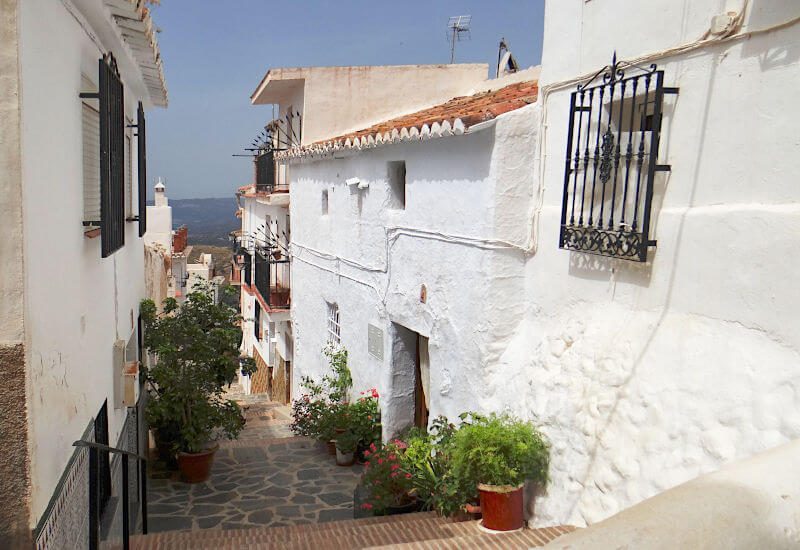 An old typical Andalusian village street leads to the house