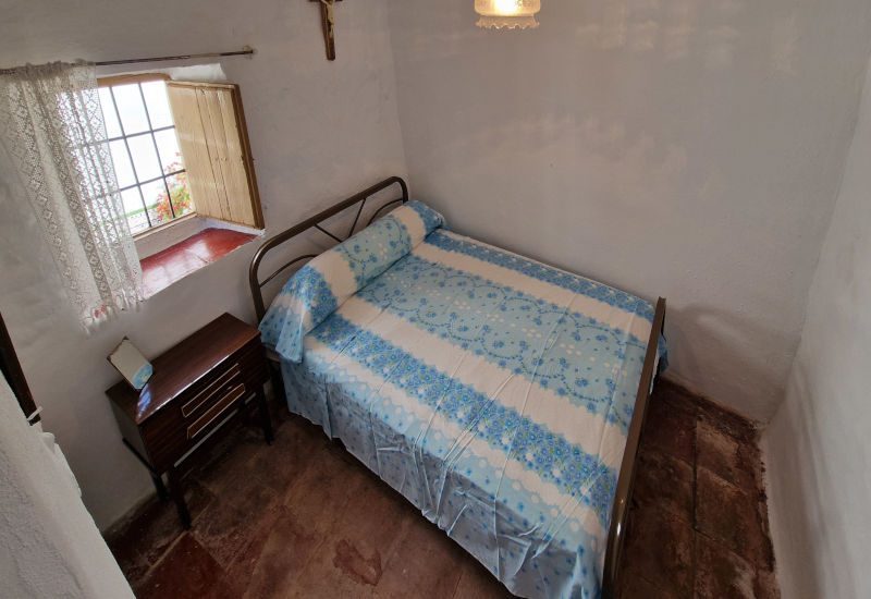 Schlafzimmer 1 mit einem Kingsize-Bett und einem kleinen Holzfenster