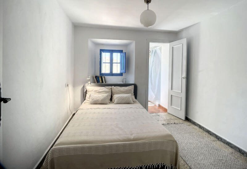 Schmales Schlafzimmer mit kleinem Fansterchen und Tür zur Zwischenterrasse