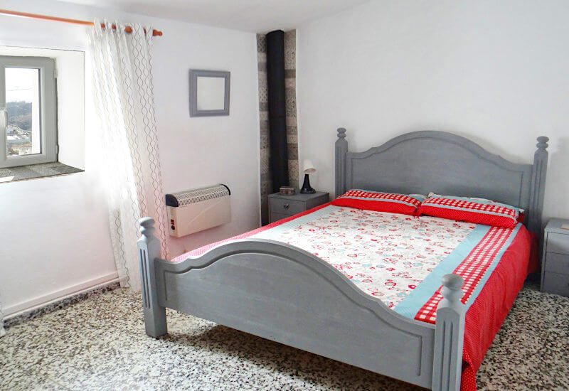 Slaapkamer met tweepersoonsbed rustiek raam op dorp en kast