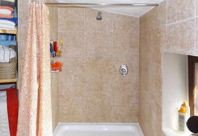 Gastendouche met meegebrachte douche en ruimte voor handdoeken.