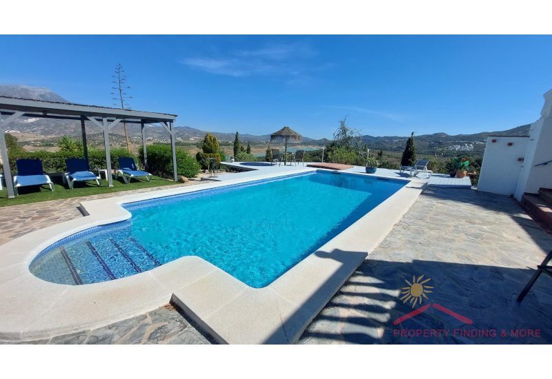 ein schöner Pool in der Sonne mit Terrasse und einem atemberaubenden Blick über die Landschaft